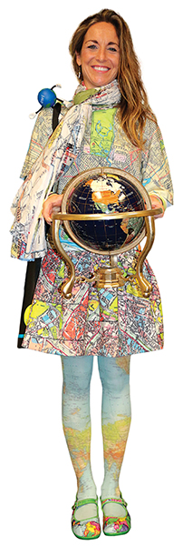 Annette Ginocchetti holding a globe while wearing a scarf, a shirt, a skirt, tights, and shoes that all have maps on them