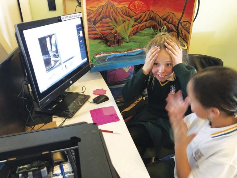A girl sitting in front of a computer with her hands on her head and a look of surprise or slight frustration on her face
