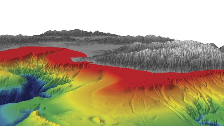 A 3D map of a canyon, some flatland, and mountains, with the mountains in gray and white tones and the rest of the scene infused with creeping colors of blue, green, yellow, orange, and red