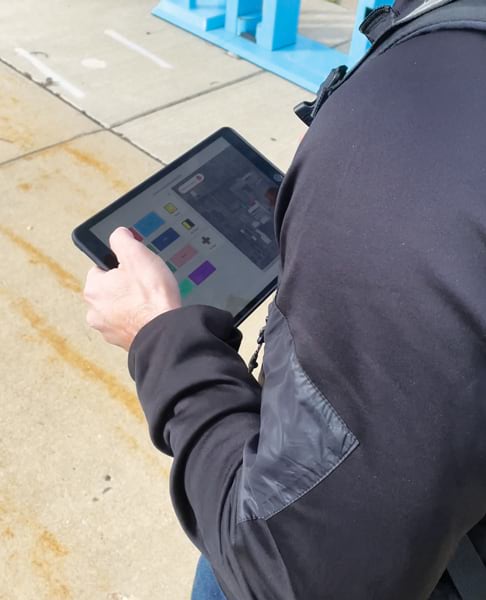 A person using ArcGIS QuickCapture on a tablet while walking along a sidewalk