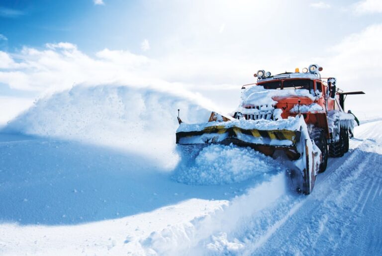 A snowplow clearing lots of snow from a street