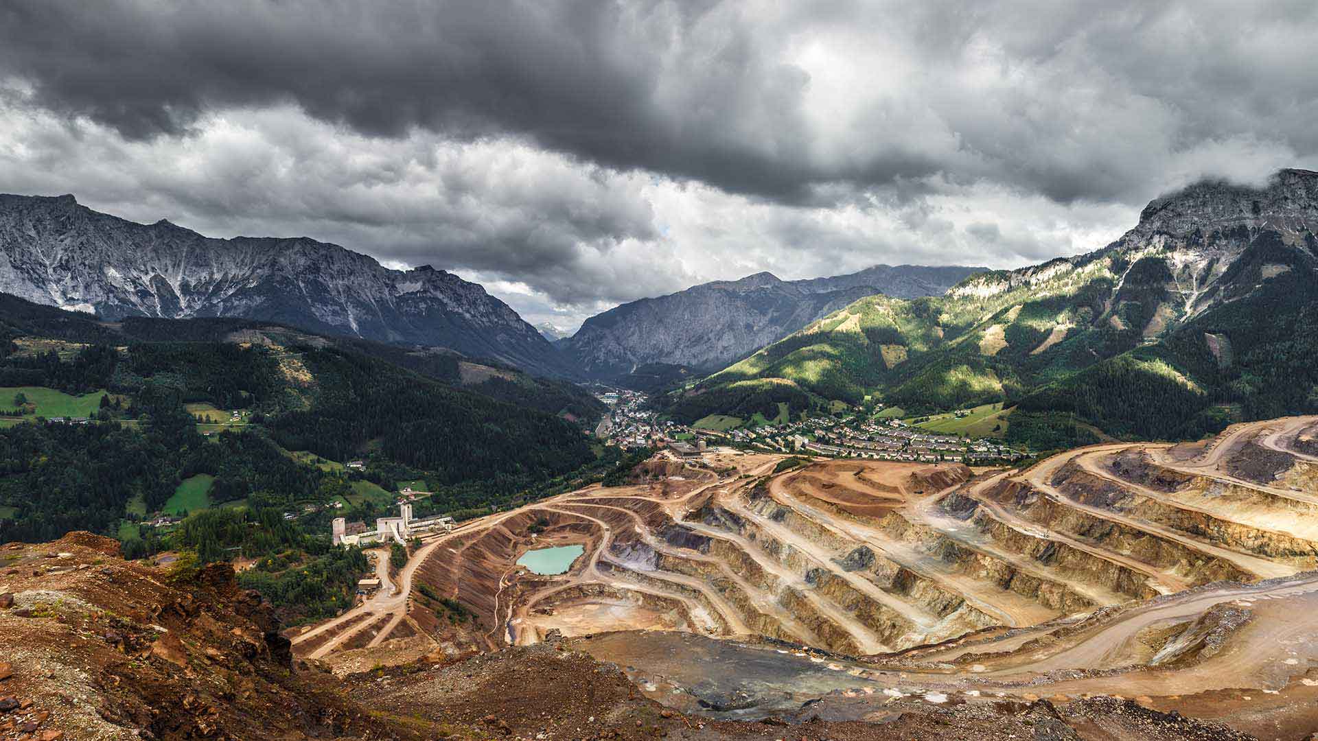 An open hillside mine with gray mountains in the background symbolizes nickel mining