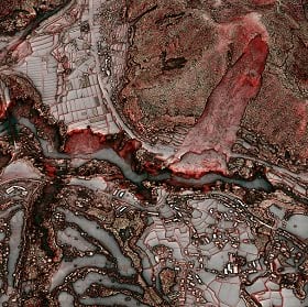 A satellite image of a brown and red landscape with property plots and a hillside