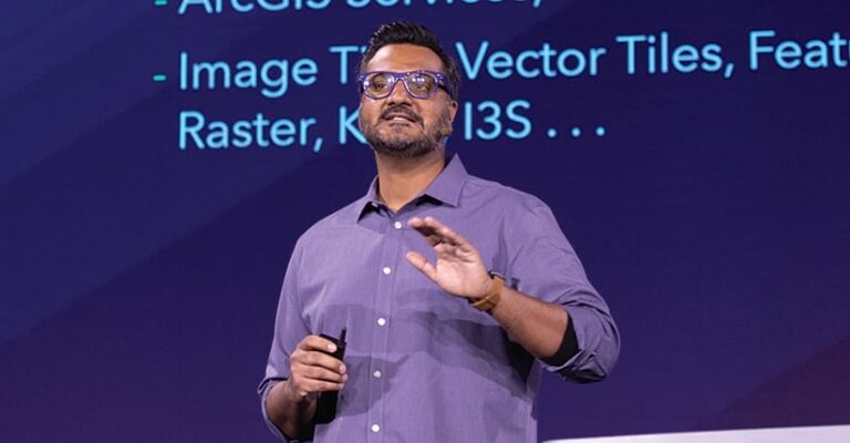 Divesh Goyal in a blue button-up shirt speaking onstage