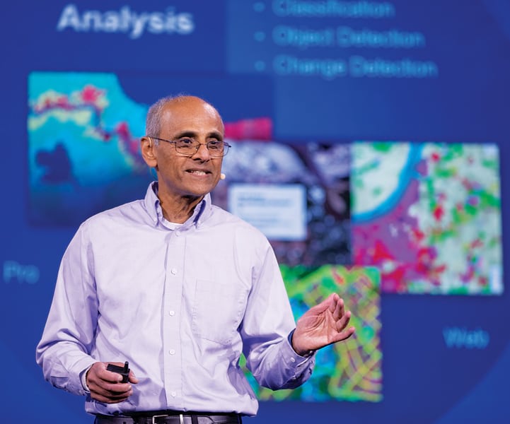 Sud Menon in a light purple-blue shirt speaking onstage