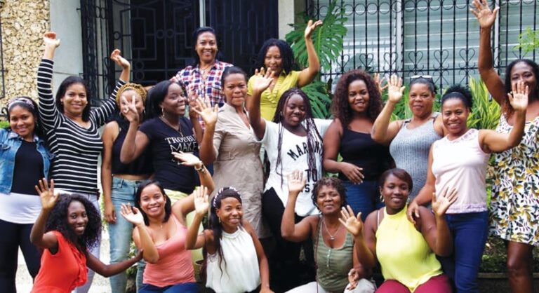 A group of women smiling and holding their hands up