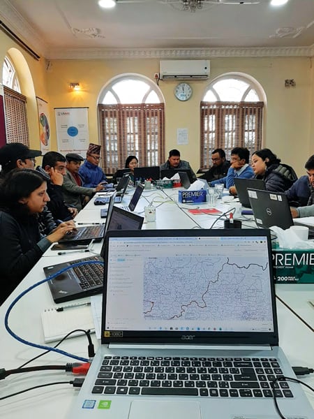 People sitting at a big table in a conference room with a laptop showing a map