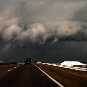 Dark storm clouds hang over a rural highway