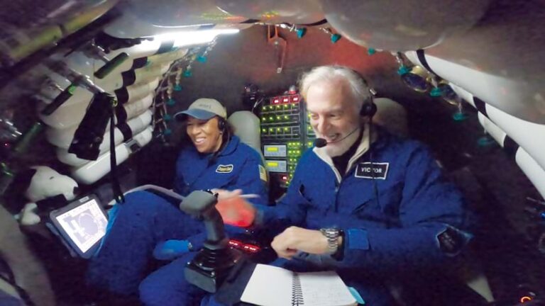 Dawn Wright and Victor Vescovo smiling in the submersible’s small chamber with instrumentation and oxygen tanks all around them