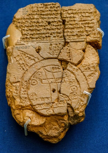 A fractured clay tablet with shapes and text inscribed on it