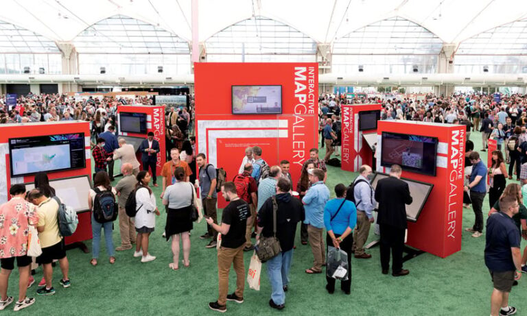 Groups of people talking in a large room with big, red displays labeled Map Gallery