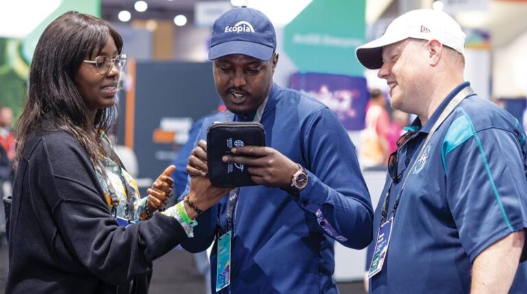 Three Esri UC attendees standing together looking at and working on a tablet