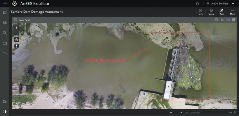 The ArcGIS Excalibur interface showing an image of a river with a dam blocked by debris and a red square encircling the debris with the words “Debris blocking dam” written in red