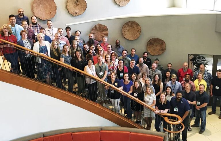 A group of more than 50 people standing on a large staircase, smiling