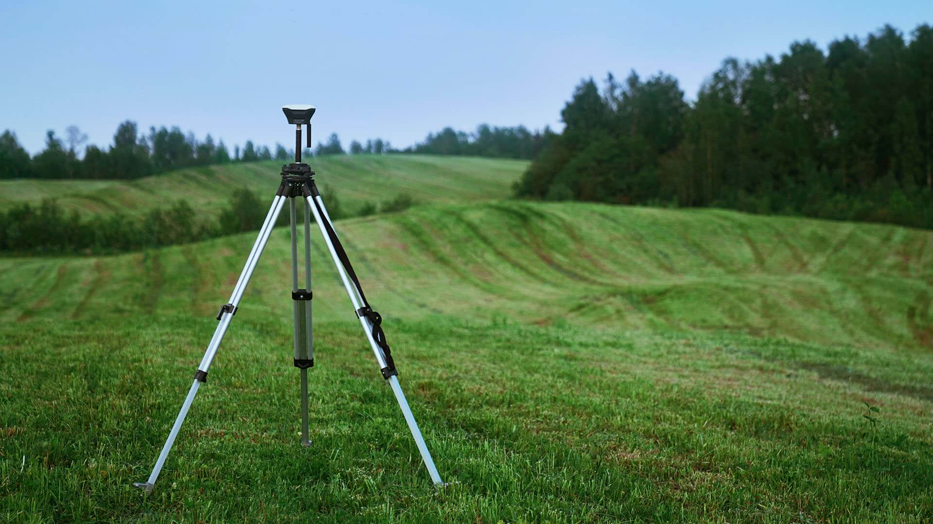 Measuring equipment on a tripod in a green rolling field