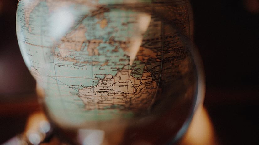 A magnifying glass over a globe symbolizes sustainable sourcing