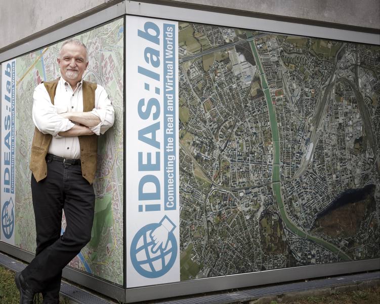 Josef Strobl standing against a sign with a map on it with his arms crossed Josef Strobl standing against a sign with a map on it with his arms crossed