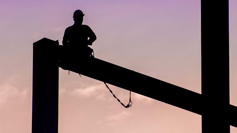 A worker in a hardhat on a beam signifies construction firms