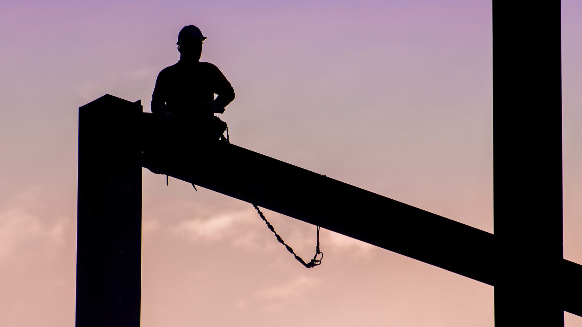 A worker in a high hat, sitting on a beam represents construction firms using location intelligence from GIS