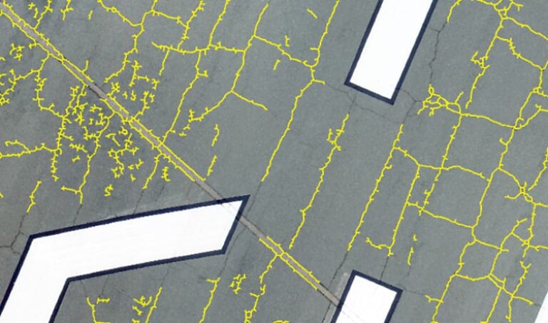 Squiggly yellow lines over a photo of asphalt showing where the cracks are located