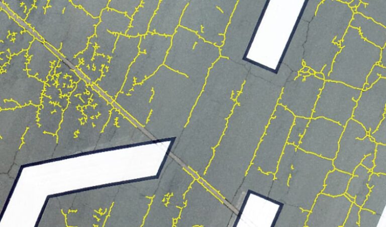 Squiggly yellow lines over a photo of asphalt showing where the cracks are located Squiggly yellow lines over a photo of asphalt showing where the cracks are located