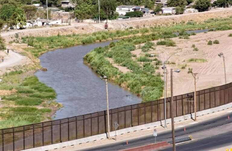 Beyond a bridge that crosses it, a river turns to the right through an arid landscape.