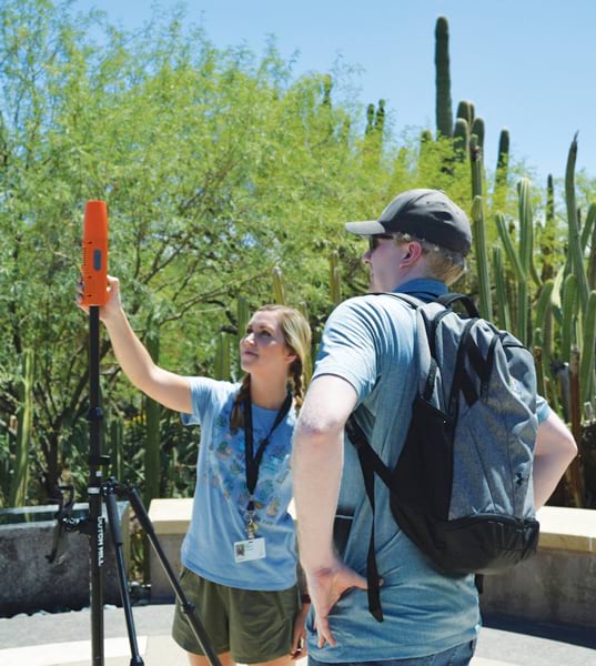 Two people using a GNSS device near some cacti