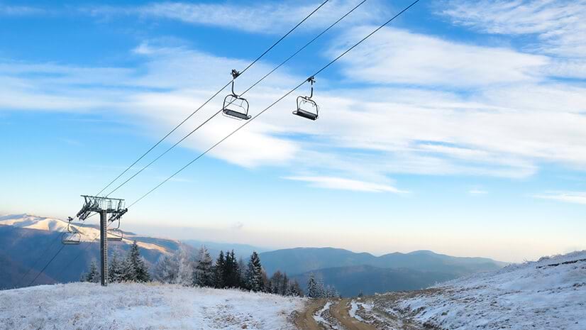 A ski resort chair lift against blue, cloud-streaked sky