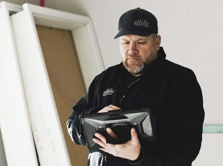 An individual in a baseball cap looks down at a handheld computer tablet.