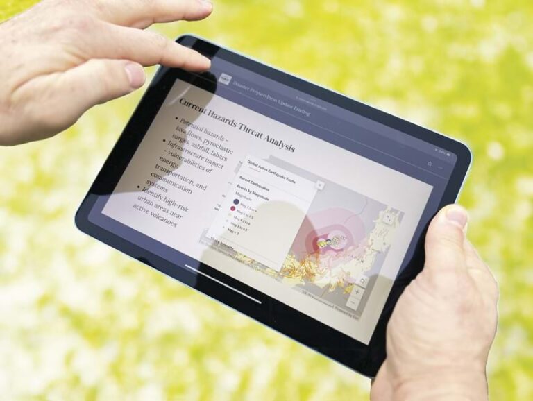 A handheld computer tablet displays a map and accompanying text.