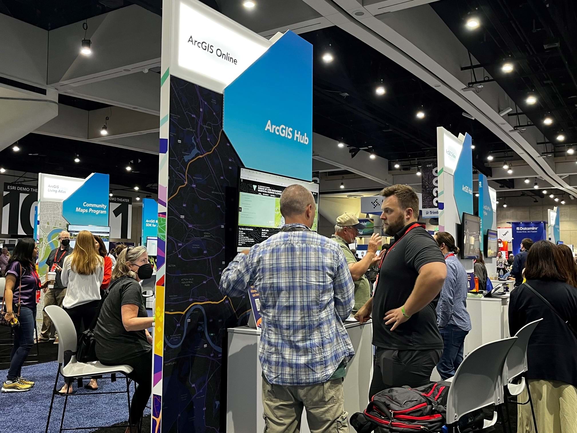 Two men looking at monitor screen at the ArcGIS Hub kiosk within the Expo are at Esri User Conference