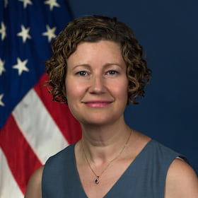 A head shot of a woman posing in front of an American flag.