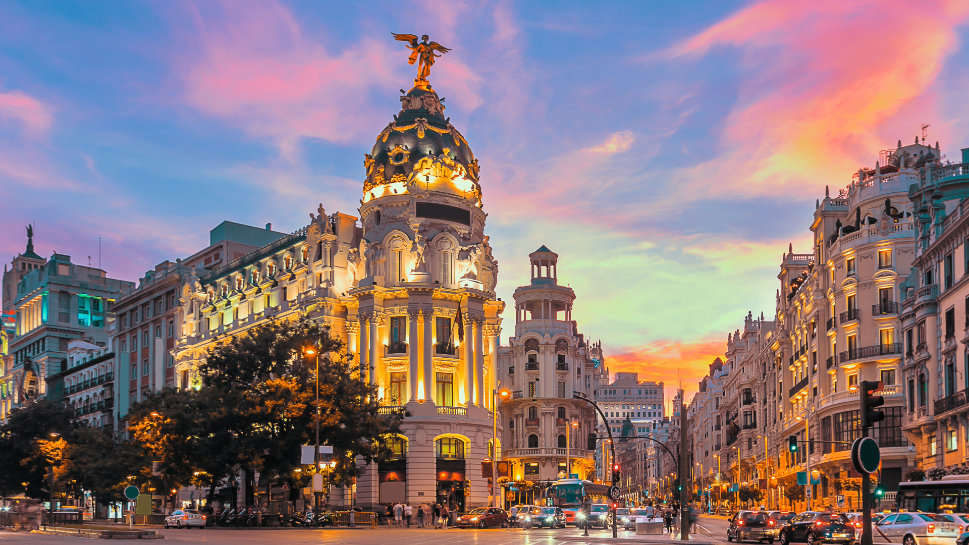 Sunset illuminates a street with a prominent landmark visible in the background