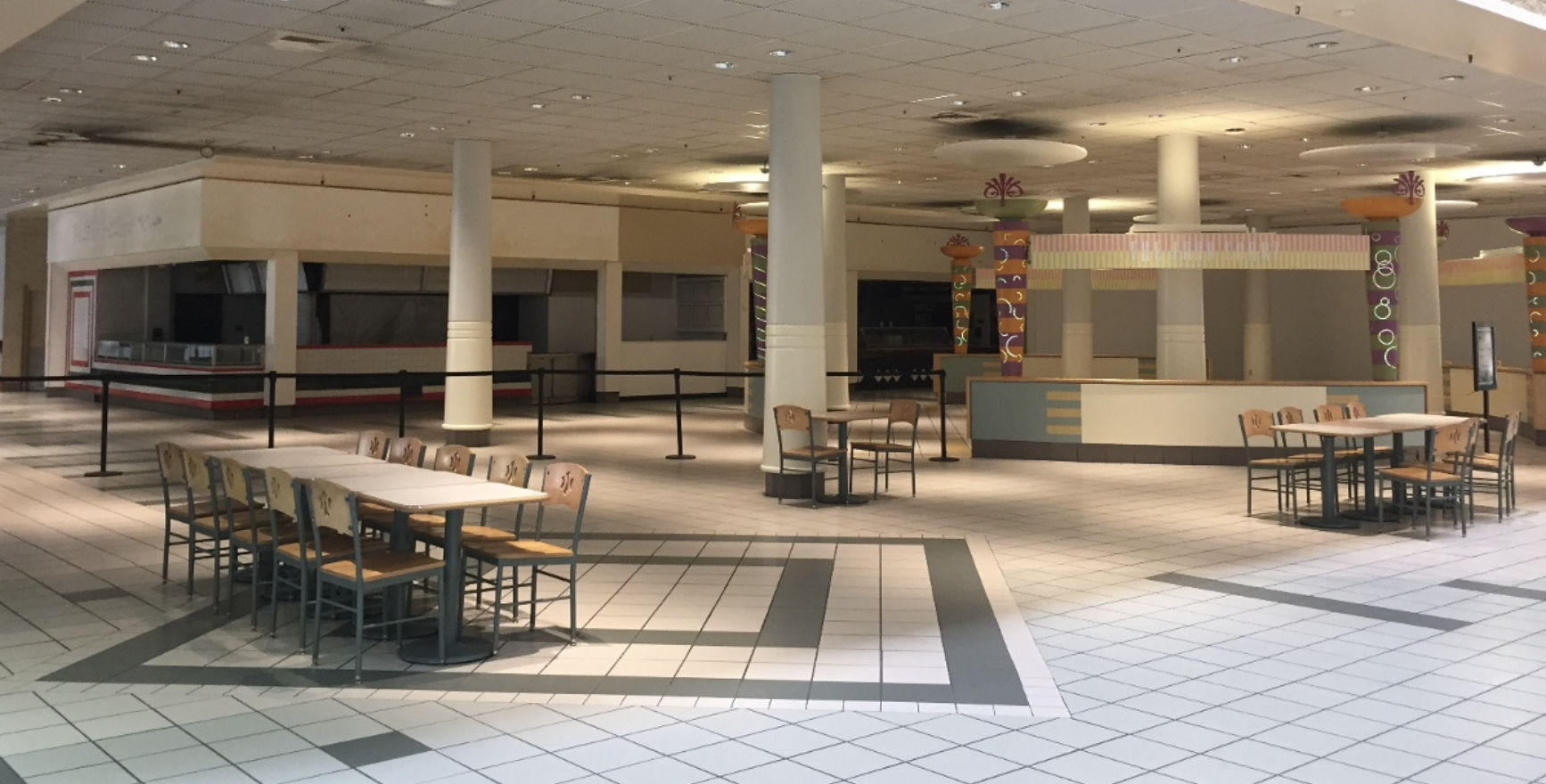 An empty mall food court, with the eatery stalls darkened and inactive.