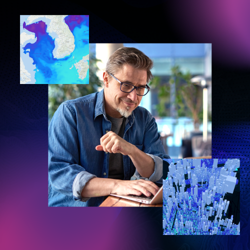 A man looking down on a computer flanked by two maps.
