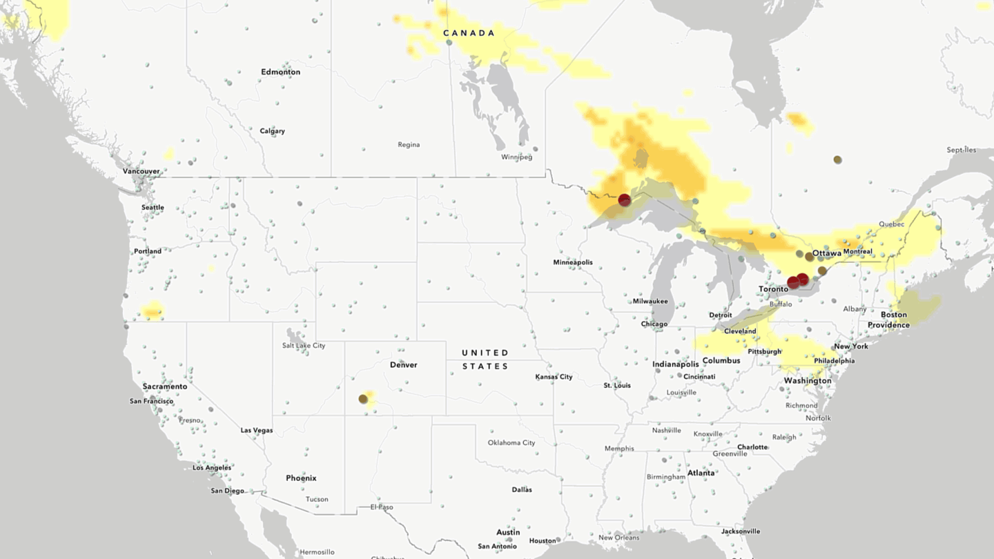 Animated map of Canada and the United States showing wildfire smoke concentrations and air quality conditions during the week of July 13, 2026. Semi-transparent yellow to orange areas represent atmospheric black carbon concentrations from NASA's GEOS-5 FP BCSMASS dataset, serving as a proxy for wildfire smoke. Colored point symbols represent OpenAQ air quality monitoring stations reporting PM2.5 concentrations, with larger and darker symbols indicating poorer air quality. Over the course of the animation, smoke plumes move eastward from active wildfire regions in central Canada toward the Great Lakes and northeastern North America. As the smoke spreads, monitoring stations within affected areas show increasing PM2.5 levels, illustrating the relationship between transported wildfire smoke and degraded air quality.