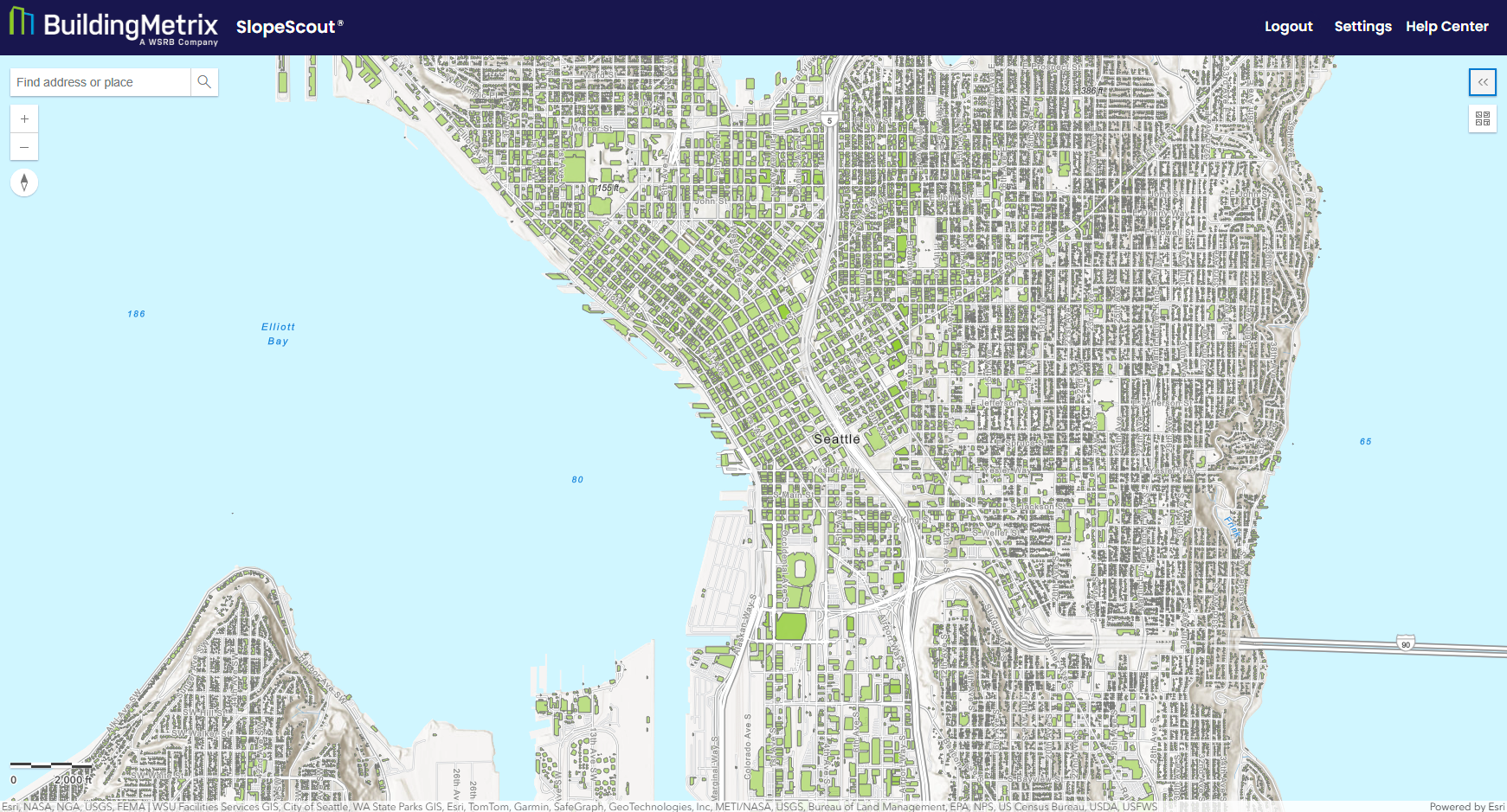 SlopeScout web application displaying a map of downtown Seattle and Elliott Bay. The interface includes a search bar, zoom controls, and navigation tools. Building footprints are highlighted in green across the city, showing property-level coverage and location analysis within an urban environment.