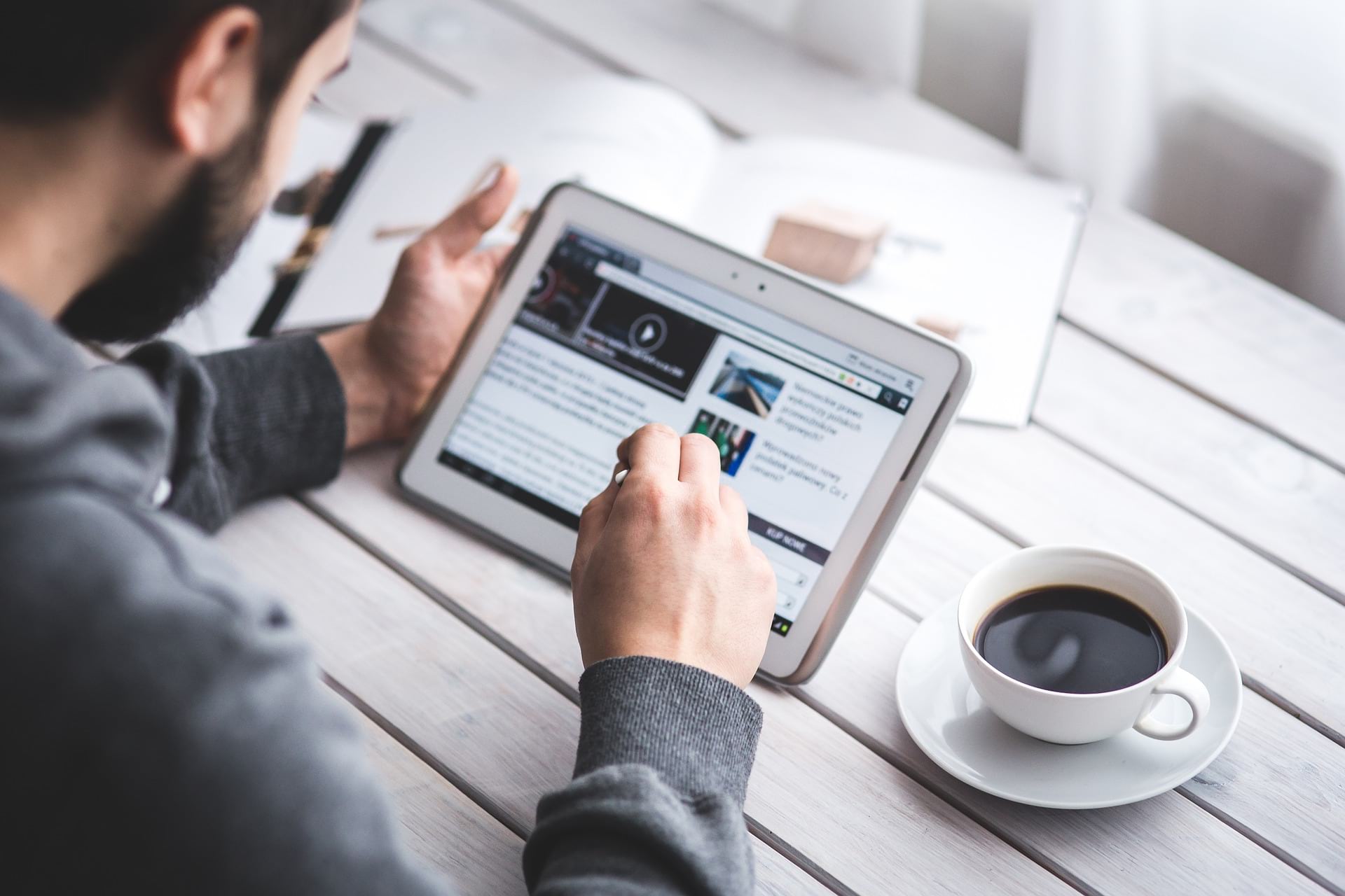 Man reading on tablet with coffee