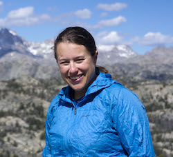 A photo of Liz Juers standing in a beautiful, mountainous landscape