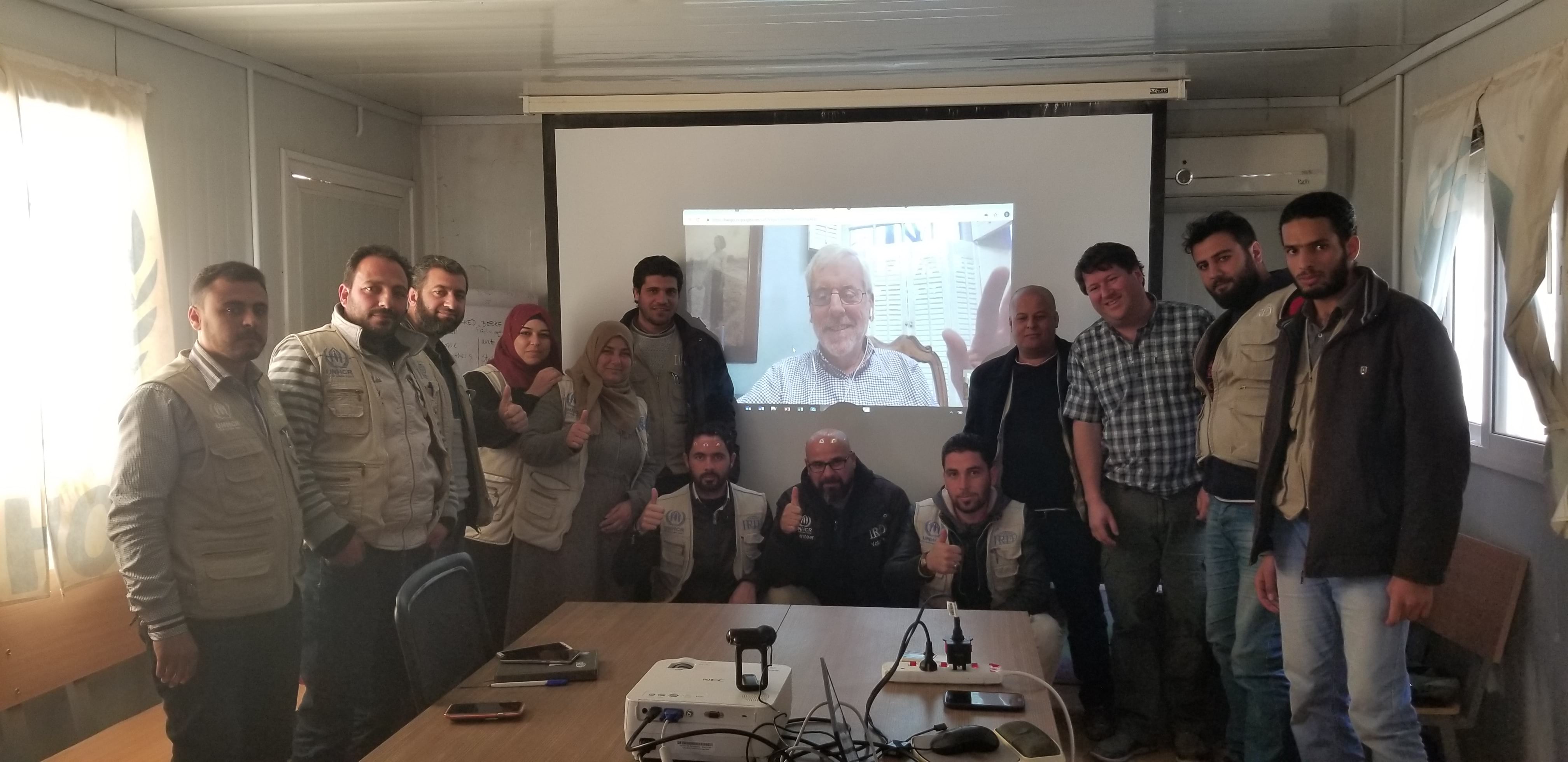RefuGIS paticipants pose for a photo next to Allen Carroll's video stream RefuGIS paticipants pose for a photo next to Allen Carroll's video stream