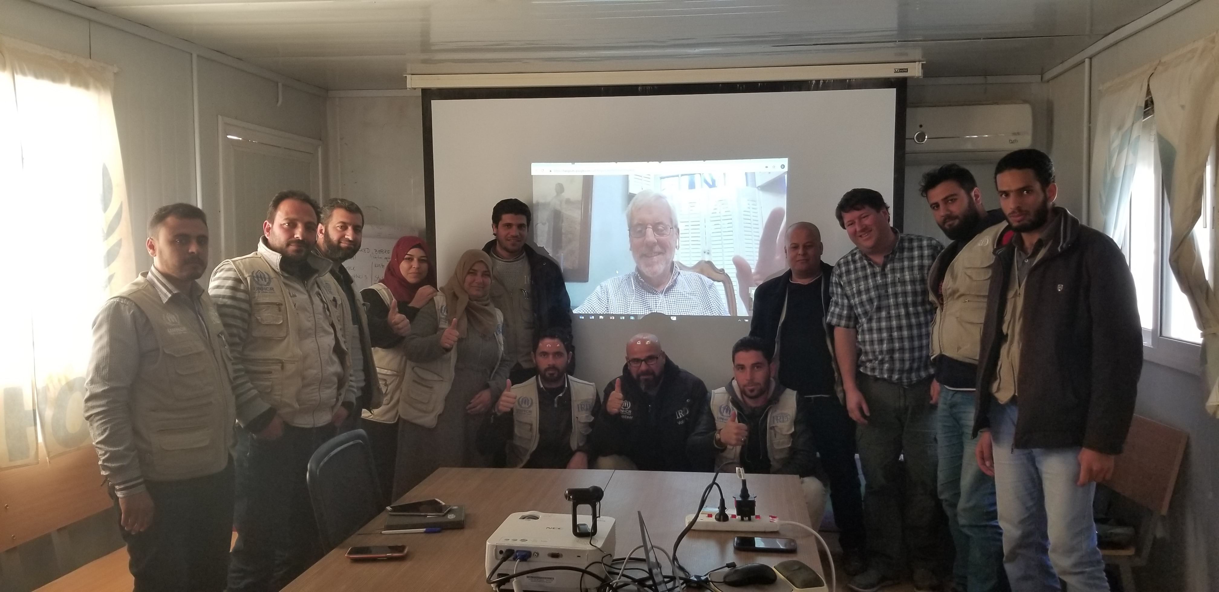 RefuGIS paticipants pose for a photo next to Allen Carroll's video stream