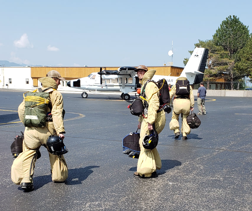 Two smokejumpers prepare to load a plane