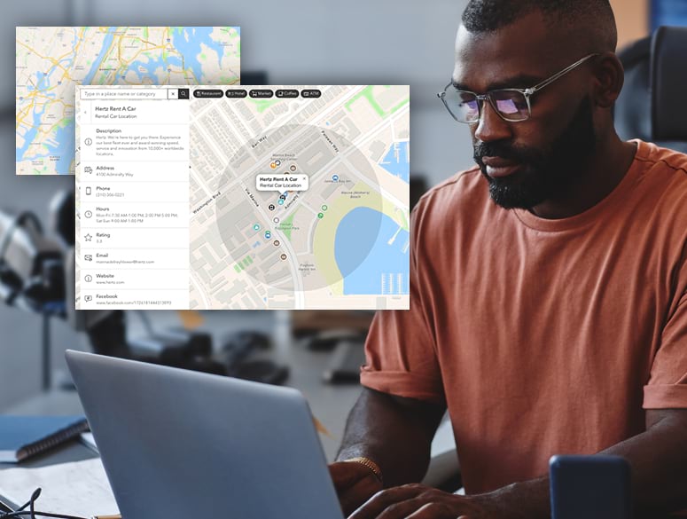 Man with glasses working on a computer. Two street map images displaying points of interest