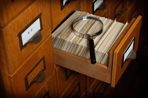 Card catalog with magnifying glass lying on an open drawer