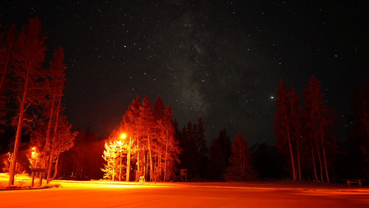 Red lights in the Colter Bay parking lot offer a darker night sky view for the public