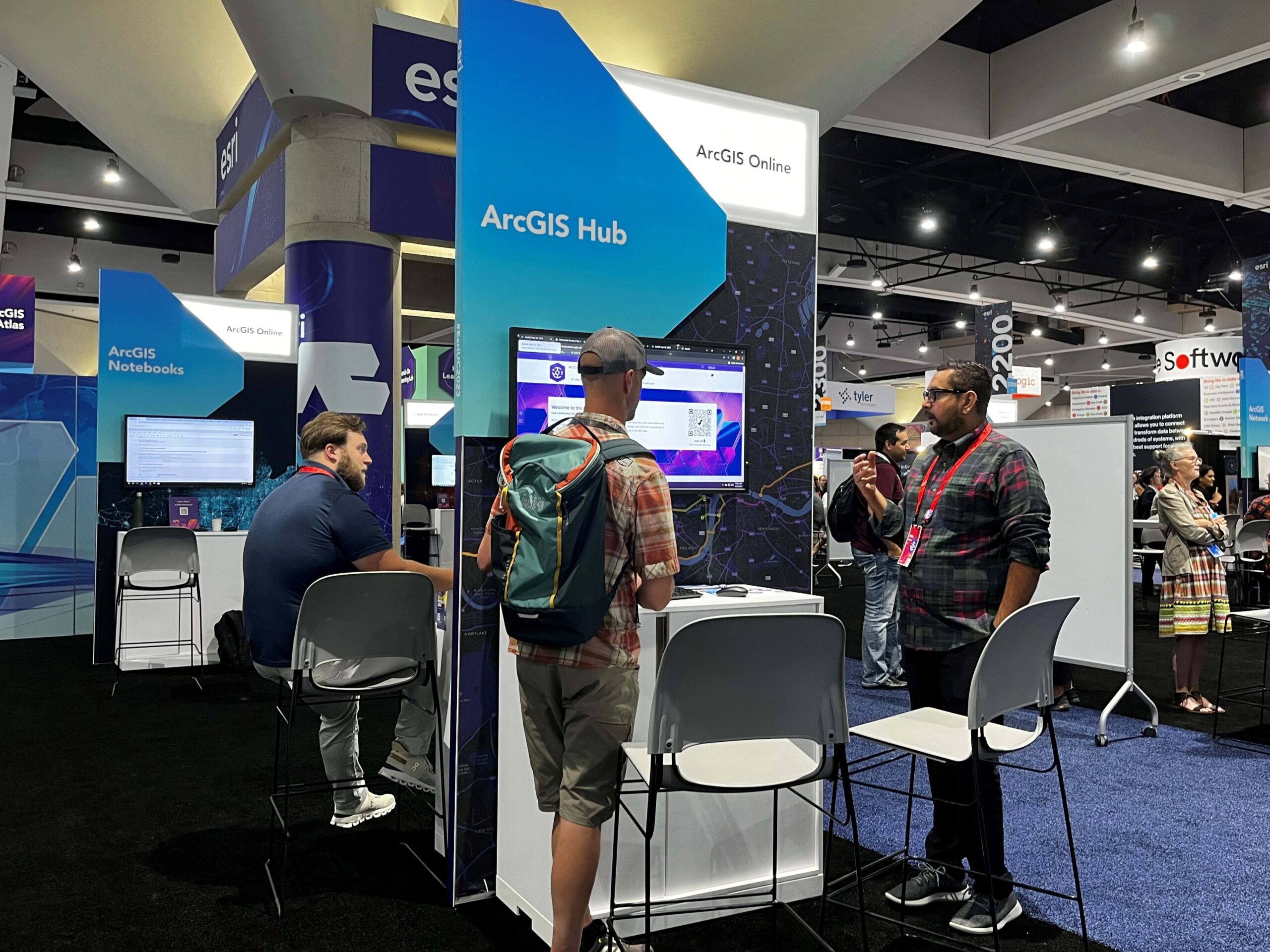 image of two people talking at a booth labeled ArcGIS Hub