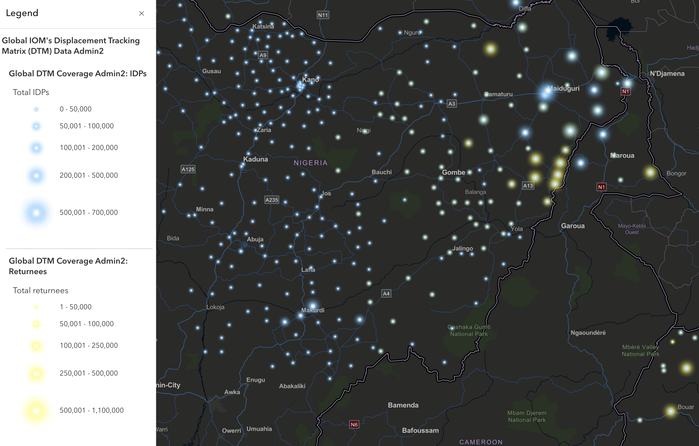 Zoomed-in black silhouette map of Nigeria showing displacement data points as blue and yellow circles of varying sizes. Blue circles represent Internally Displaced Persons (IDPs), and yellow circles represent returnees. A legend on the left indicates ranges: smallest circles for totals up to 50,000, largest blue circles for up to 700,000 IDPs, and largest yellow circles for up to 1,100,000 returnees.