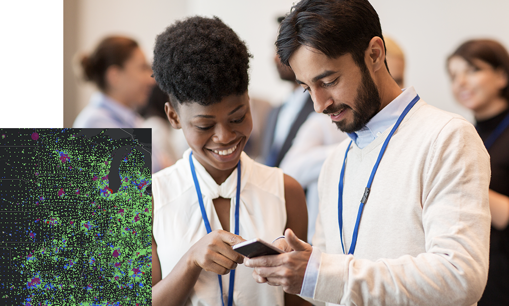 University students smiling while looking at a mobile device with a digital map