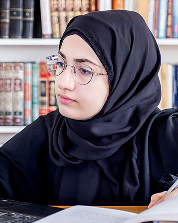 Student wearing glasses and a head scarf while studying