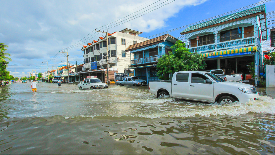 Cars driving down a flooded street lined with buildings